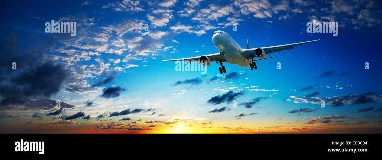 Jet plane in a sunset sky. Panoramic composition in high resolution. Stock Photo