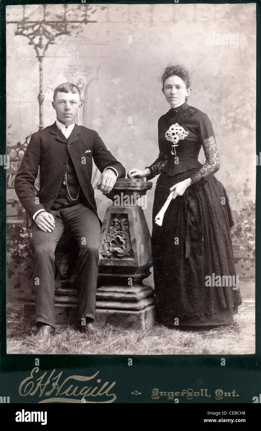 Vintage photo of couple posing in photography studio, 1890s1910 dressed in formal clothing of
