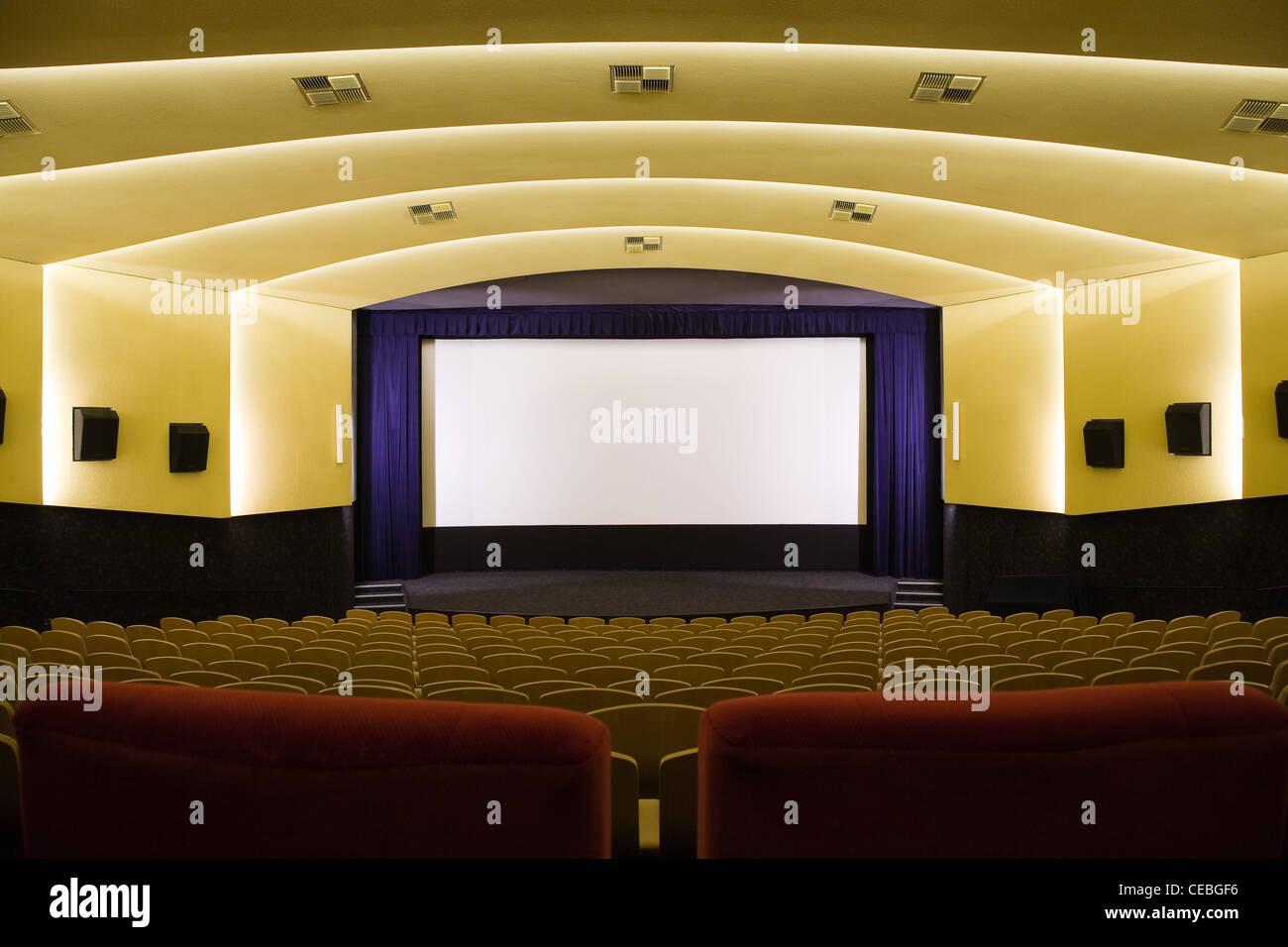 Empty cinema auditorium with line of chairs and projection screen ...