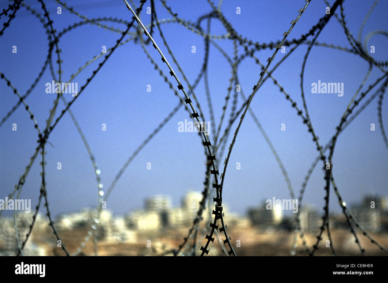 Coiled barbed wire fence separating Jewish settlement and Arab town in East Jerusalem Israel Stock Photo