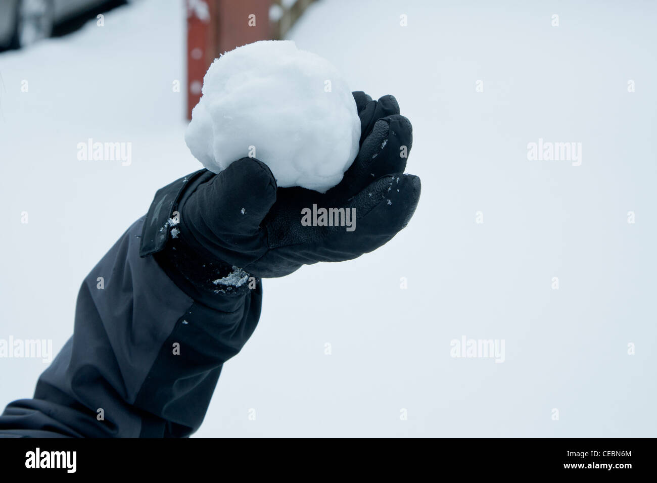 A child's gloved hand holds a snowball ready to throw it Stock Photo