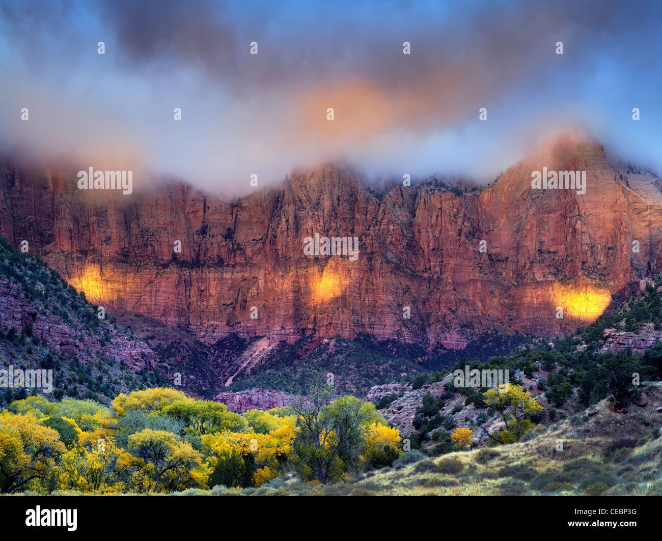Sunrise peaking through storm clouds.with fall color Towers of the Virgin. Zion National Park, Utah Stock Photo