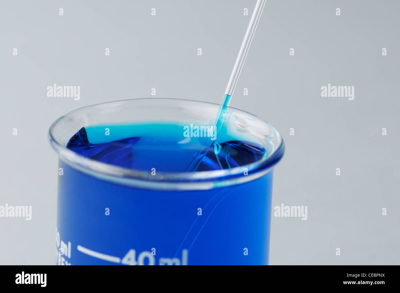 Blue colored water moves up a capillary tube demonstrating capillary action caused by adhesion (see description) Stock Photo