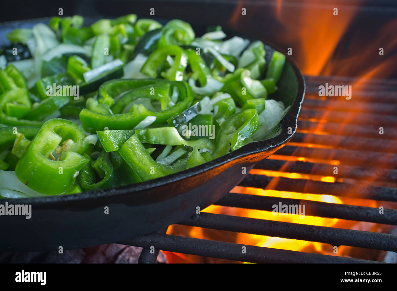 Green Peppers cooking in cast iron skillet over open fire Stock Photo