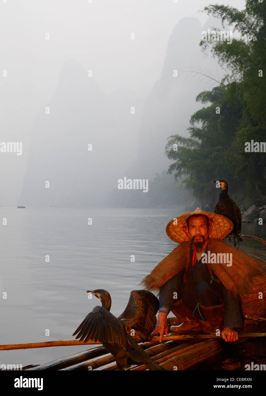 Cormorant fisherman on a bamboo raft on the Li river with Karst mountain peaks Xingpingzhen Yangshuo, Guilin, Guangxi China Stock Photo