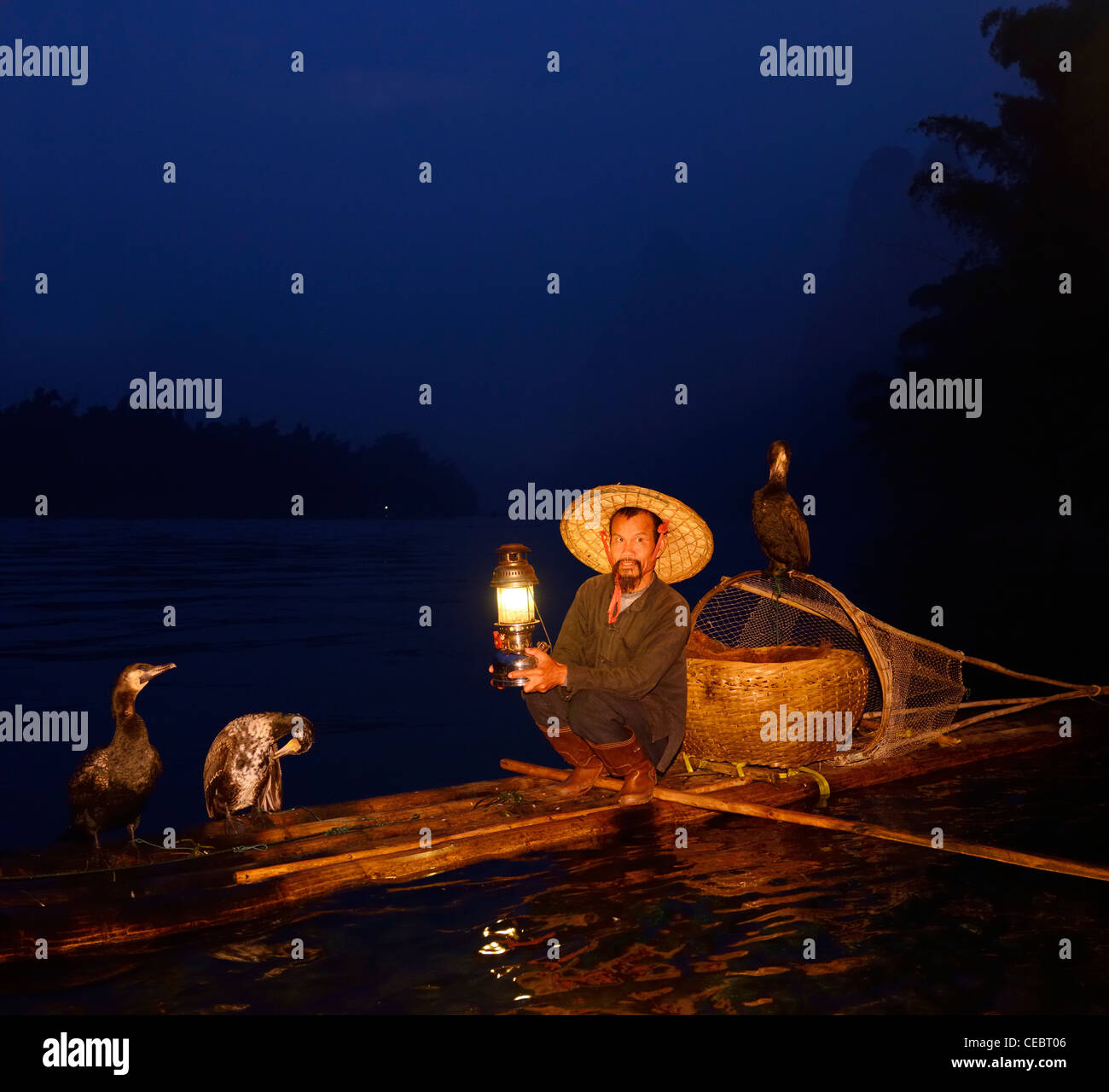 Cormorant fisherman with lamp on bamboo raft at dawn on Li or Lijiang river Xingpingzhen Yangshuo, Guilin, Guangxi China Stock Photo