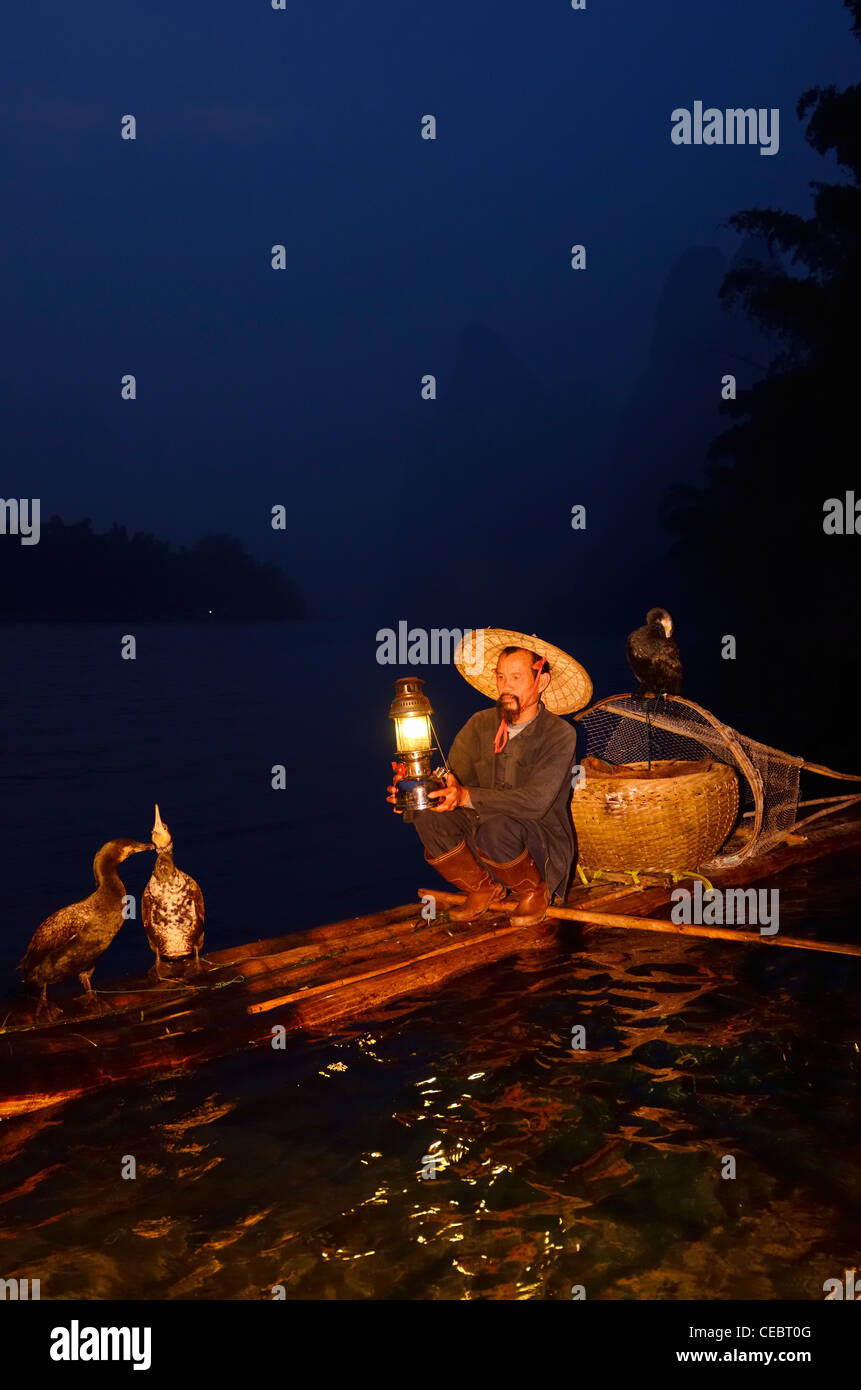 Early morning Cormorant fisherman with lamp on bamboo raft on Li or Lijiang river Xingpingzhen Yangshuo, Guilin, Guangxi China Stock Photo
