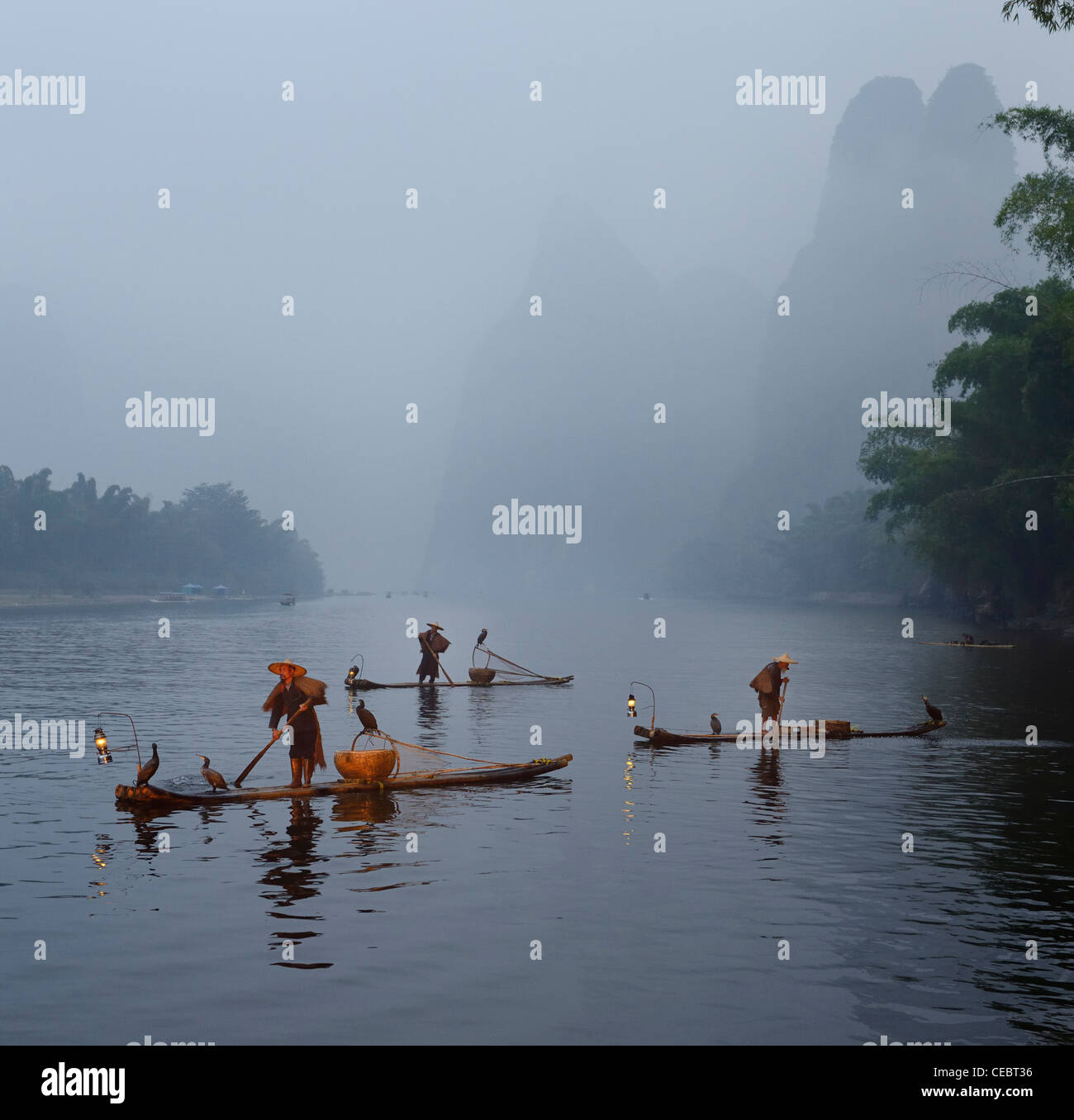 Cormorant fishermen in morning mist on the Li river with Karst mountain peaks Xingpingzhen Yangshuo, Guilin, Guangxi China Stock Photo
