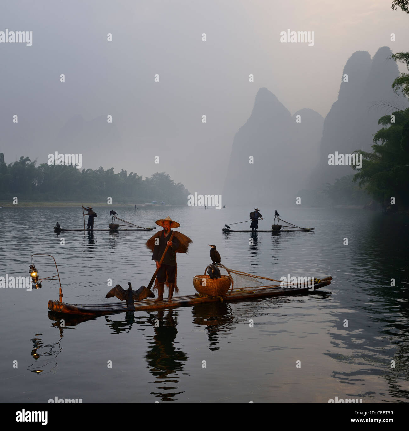 Cormorant fishermen in bamboo rafts at sunrise on the Li river with Karst mountain peaks near Xingping China Stock Photo