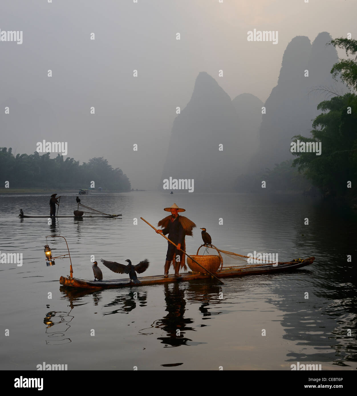 Cormorant fishermen paddling bamboo rafts at dawn on the Li river with Karst mountain peaks Xingpingzhen Yangshuo, Guilin, Guangxi China Stock Photo