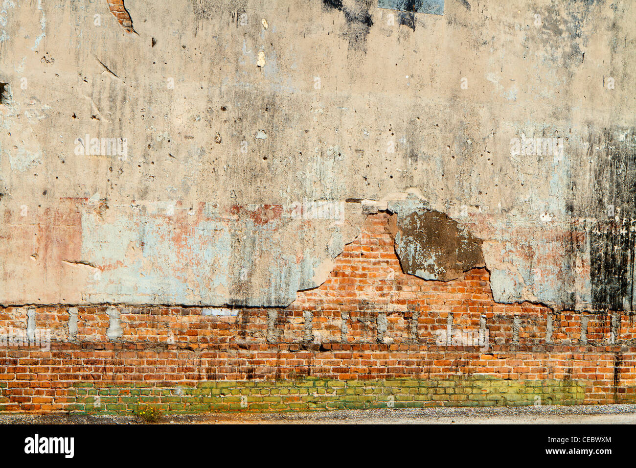 A weathered, grungy, dirty, cement covered brick wall in a city back