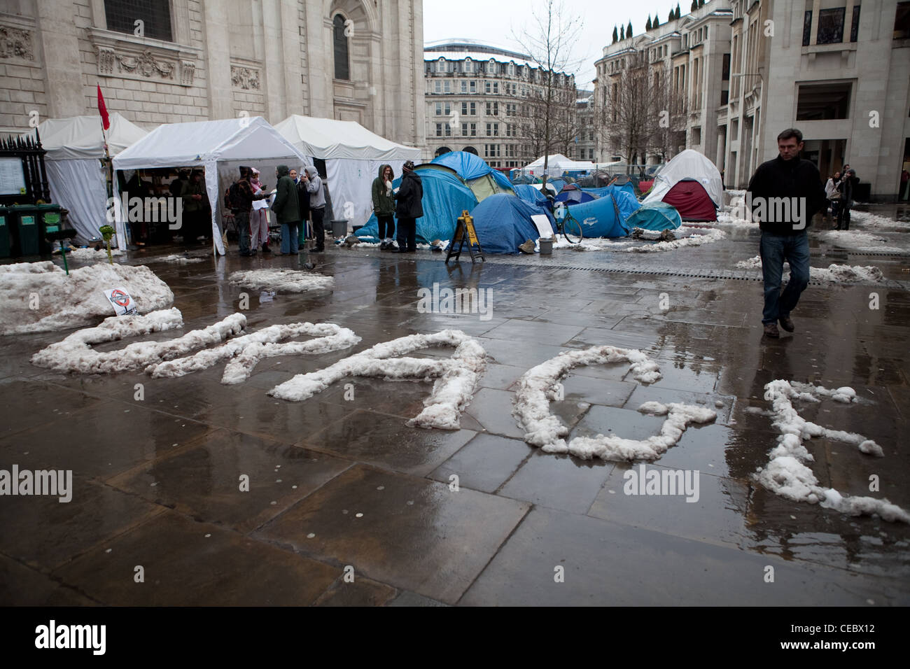 Scene of St Paul's occupation camp. The word 'courage' is written in snow with camping tents behind. Stock Photo