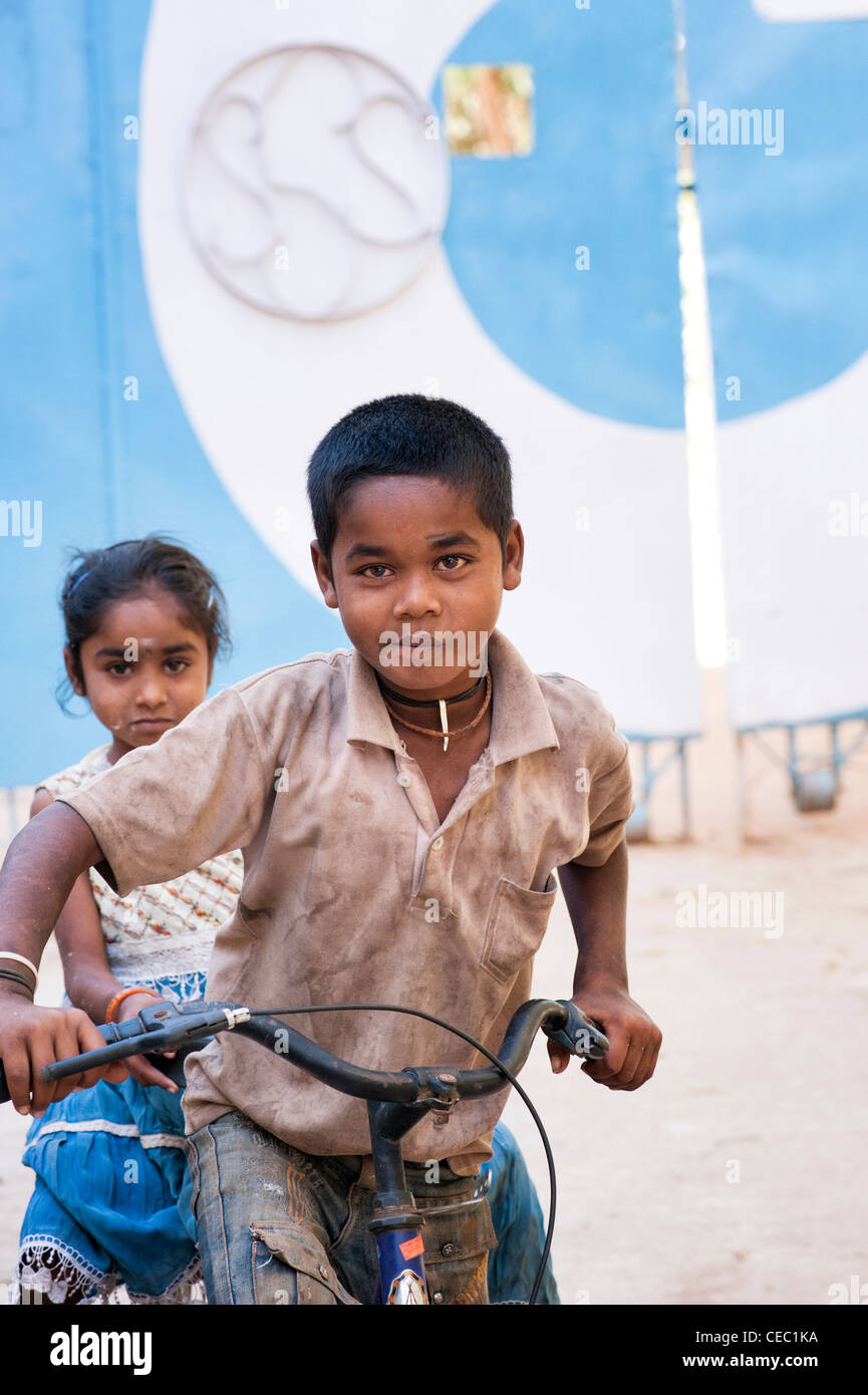 Young poor lower caste Indian street boy and girl riding a bicycle. Puttaparthi, Andhra Pradesh, India Stock Photo