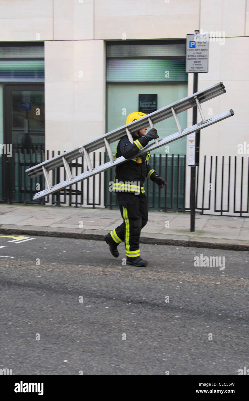 Firefighter carrying a short extension ladder Stock Photo Alamy