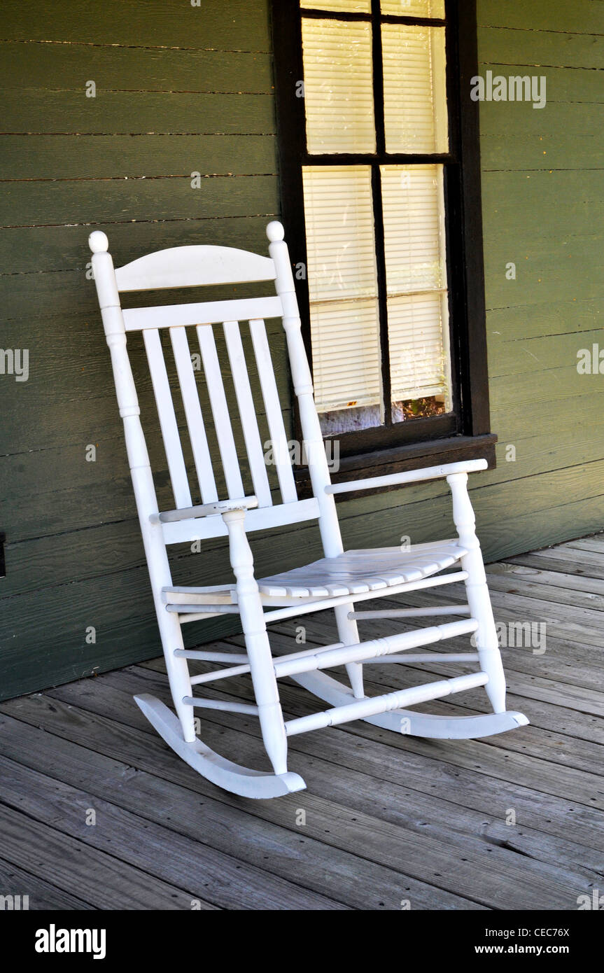 A white wooden rocking chair is sitting on the front porch Stock Photo