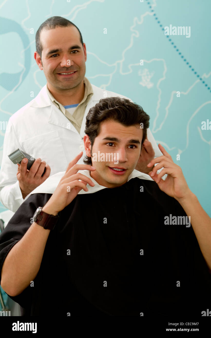 Hispanic Barber listening to client in barber shop Stock Photo