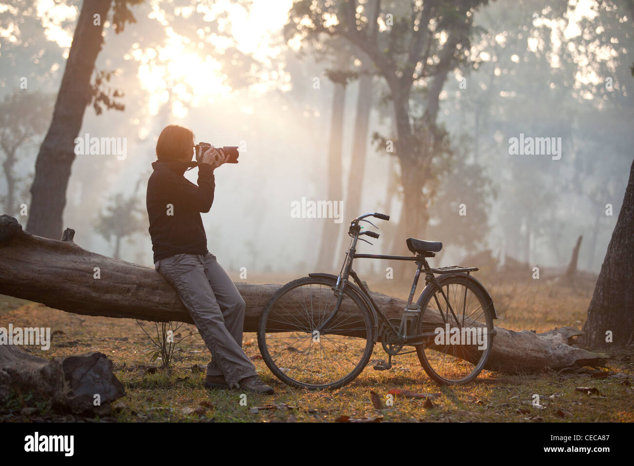 Woman photographing bike with sunrise forest Bardia Nepal Asia Stock Photo