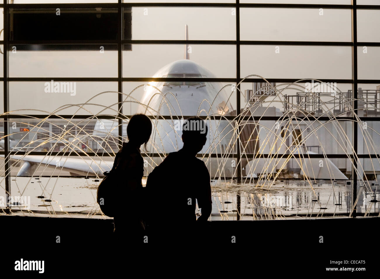 Silhouetted passersby admire an animated fountain juxtaposed with a Boeing 747 aircraft at the McNamara Terminal Stock Photo