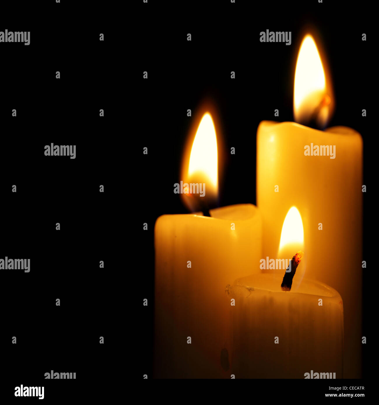 Three burning candles over a black background Stock Photo - Alamy