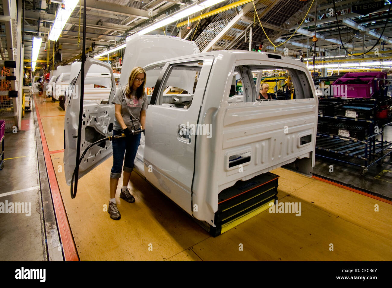 A woman factory worker uses a power operated wrench to install door hardware on an F-150 pickup truck at the Ford final assembly Stock Photo
