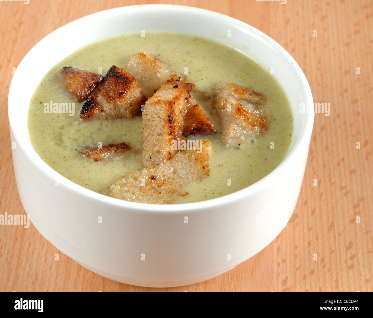 Broccoli cream soup with croutons  in a white dish on a wood table. Stock Photo