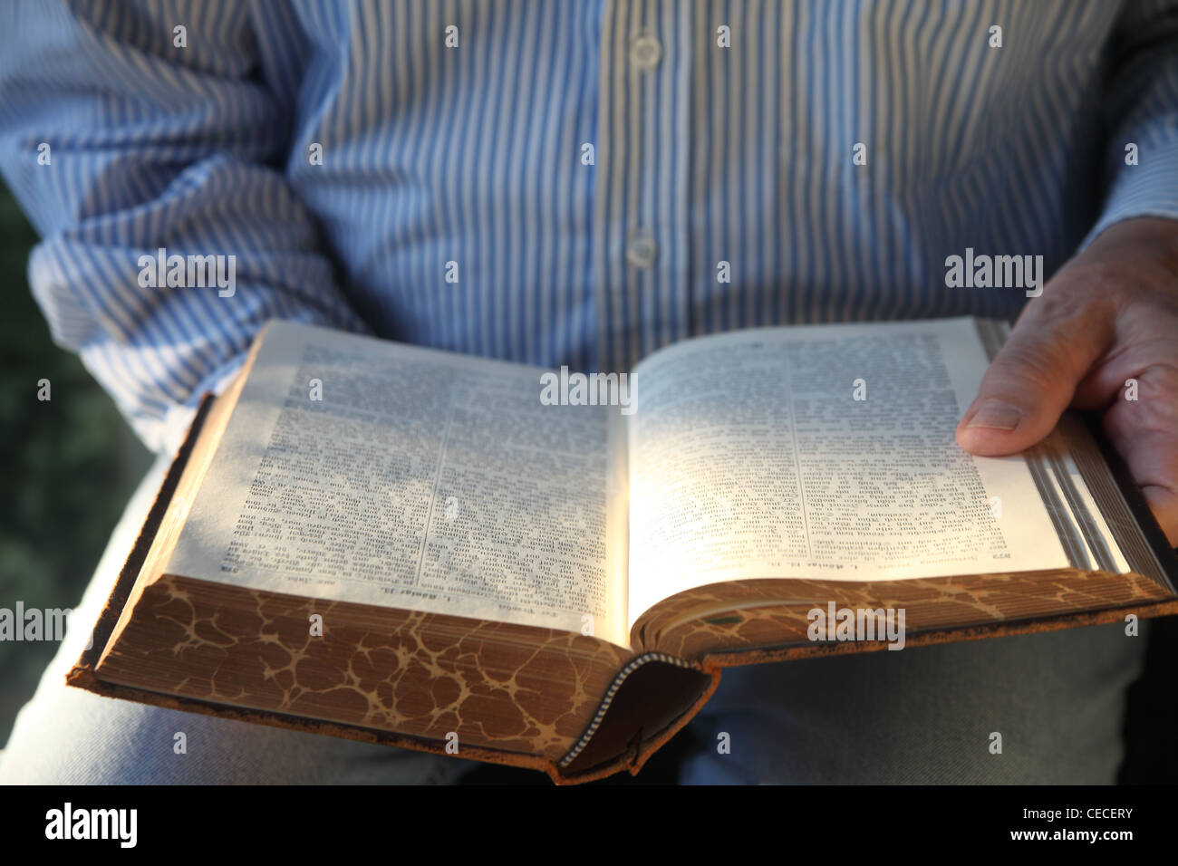 a man reads a 1904 Bible as sunlight glows on the pages Stock Photo