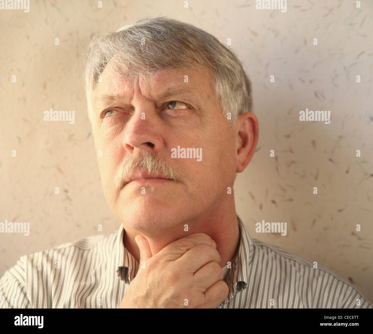 older man rubs his sore throat Stock Photo