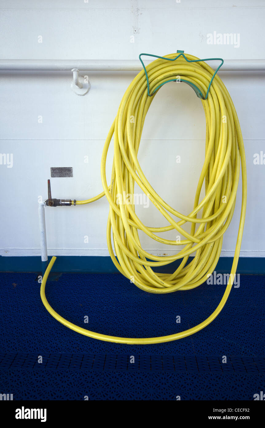 Yellow hose pipe hanging on ferry wall Stock Photo