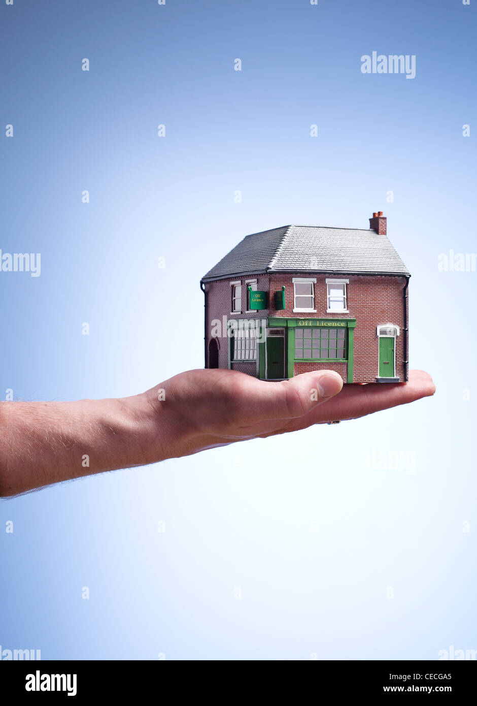 Hand holding a toy house / off licence Stock Photo