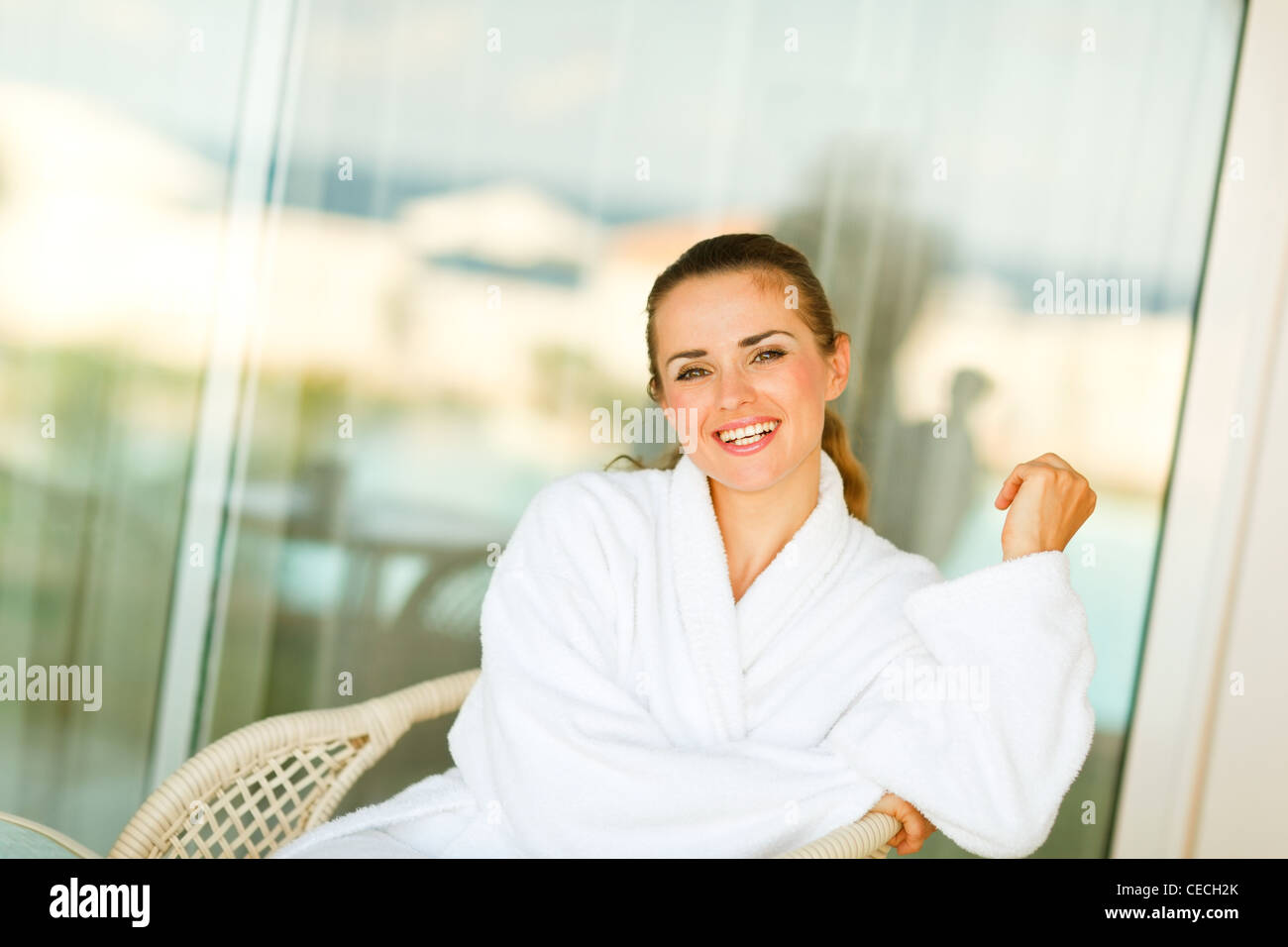 Portrait of smiling woman in bathrobe sitting on terrace Stock Photo