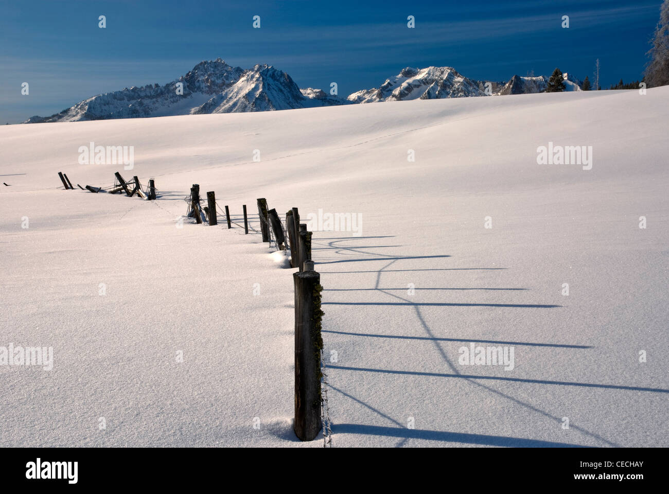 A Barbed Wire Fence covered with snow in the mountains Stock Photo