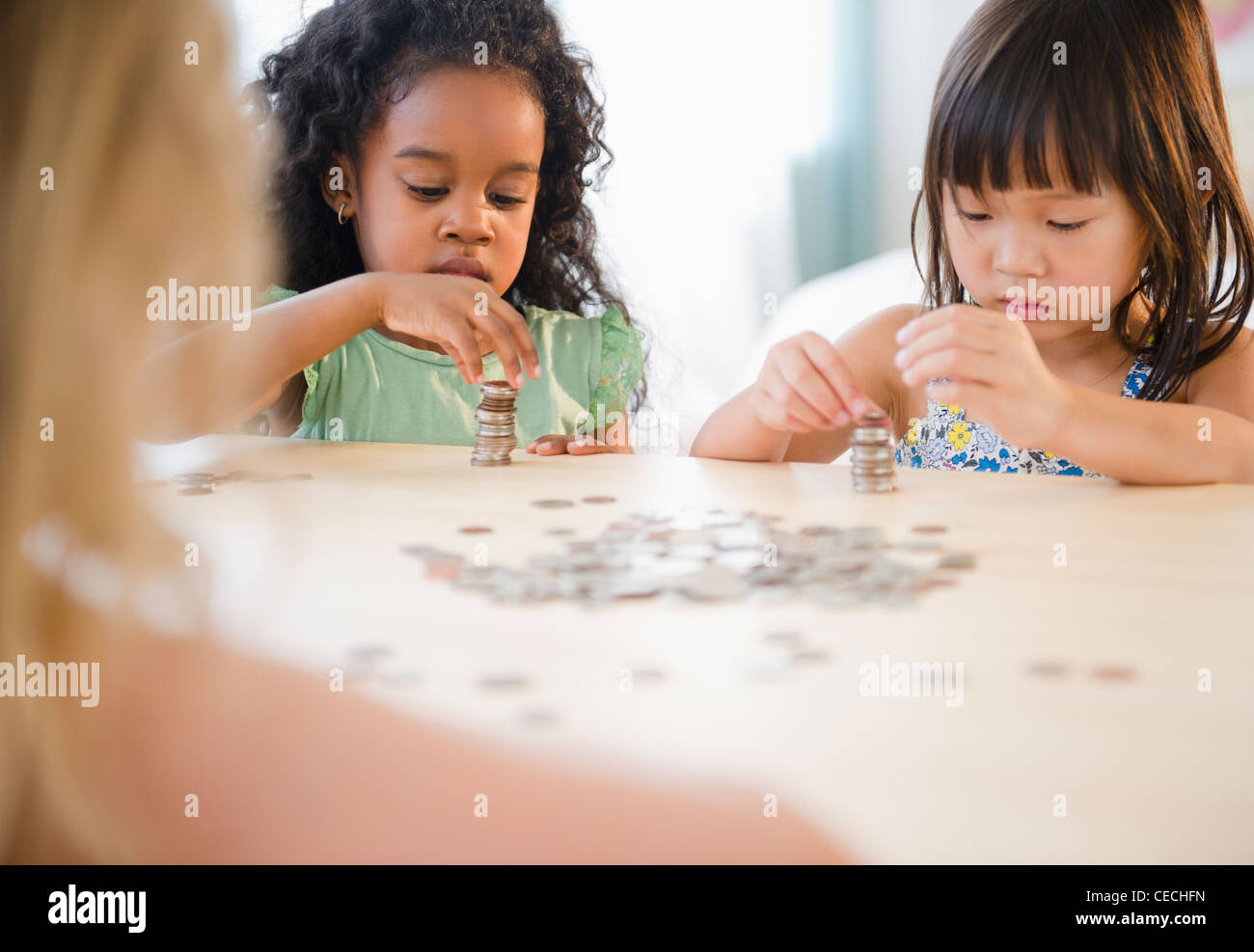 Girls stacking coins together Stock Photo - Alamy