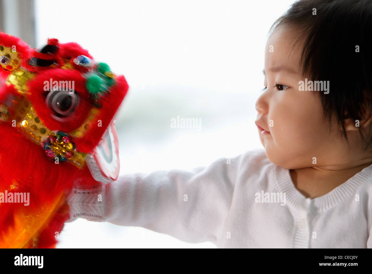 profile of baby looking at Chinese dragon toy Stock Photo