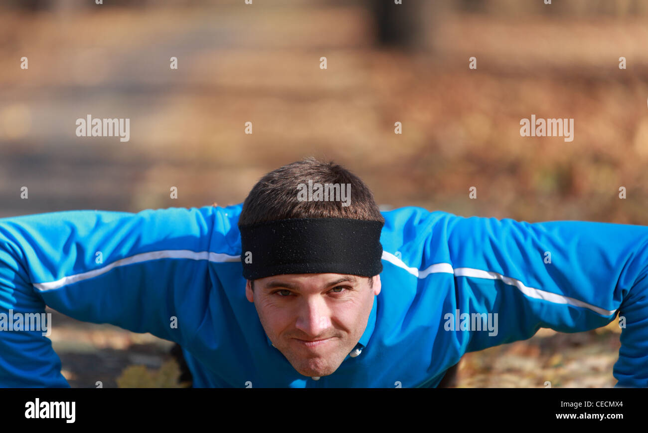 Portrait of a young man doing push-up outdoors in a park in autumn ...