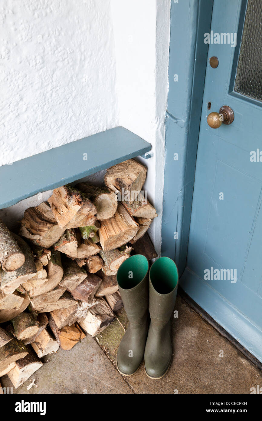 Green wellington boots alongside firewood in a porchway Stock Photo - Alamy