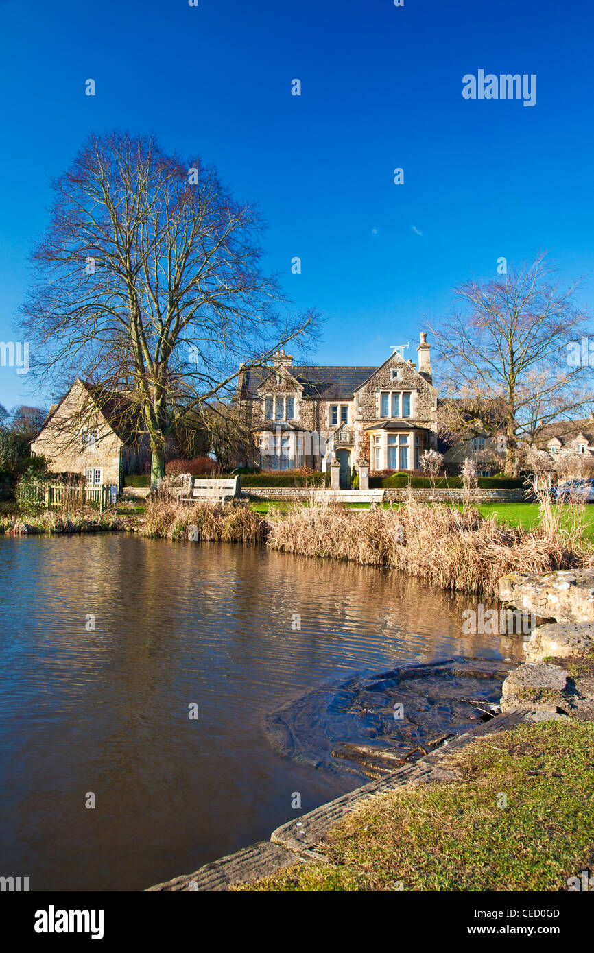 Houses around a typical English village duck pond on the green in Biddestone, Wiltshire, England, UK Stock Photo