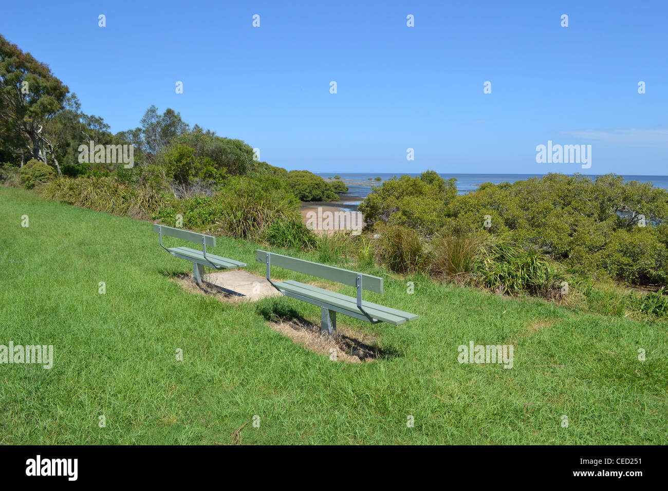 Two wooden seats facing the ocean Sandstone Point, Queensland, Australia Stock Photo