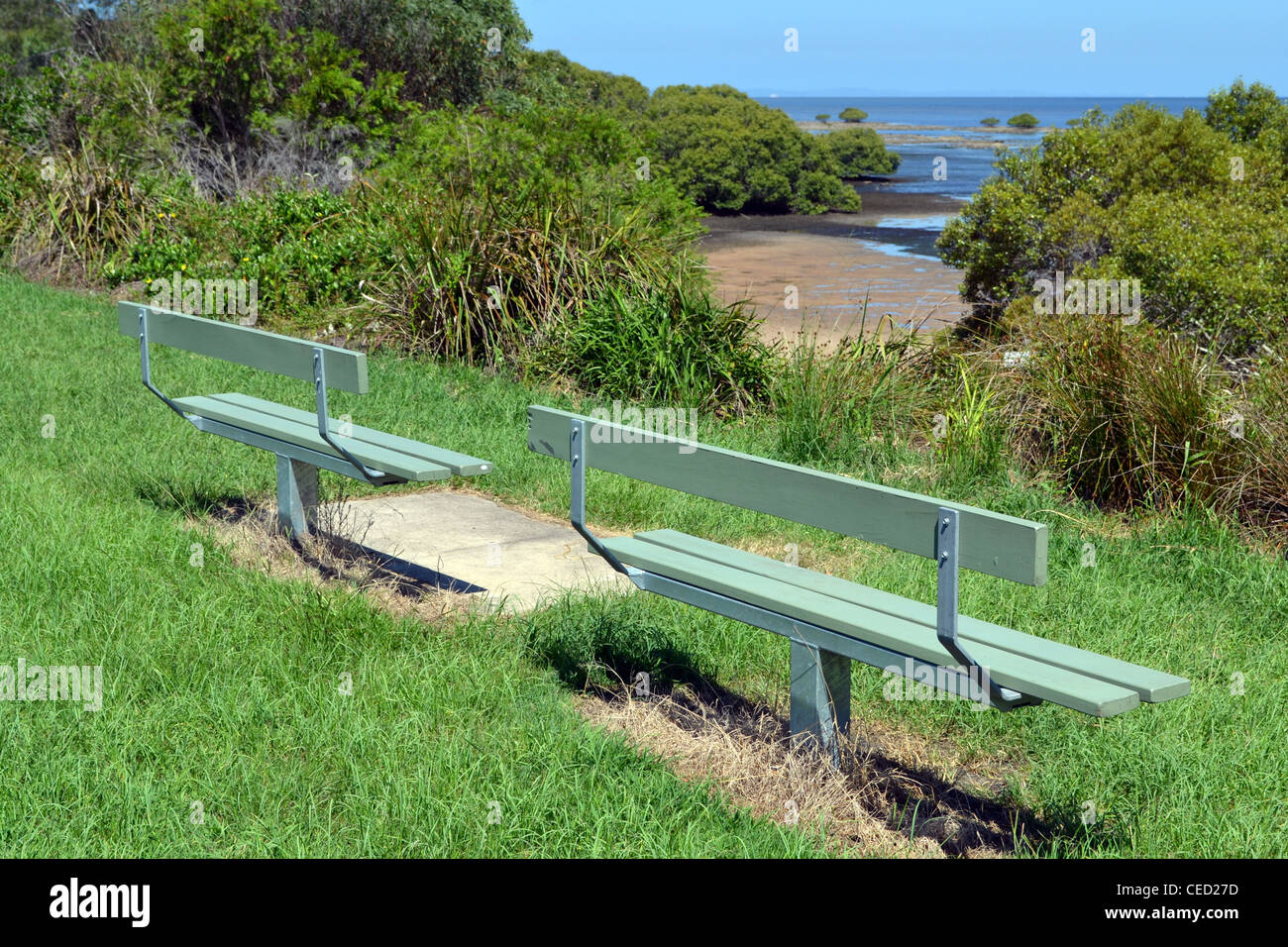 Two empty wooden seats facing the ocean Sandstone Point, Queensland, Australia Stock Photo