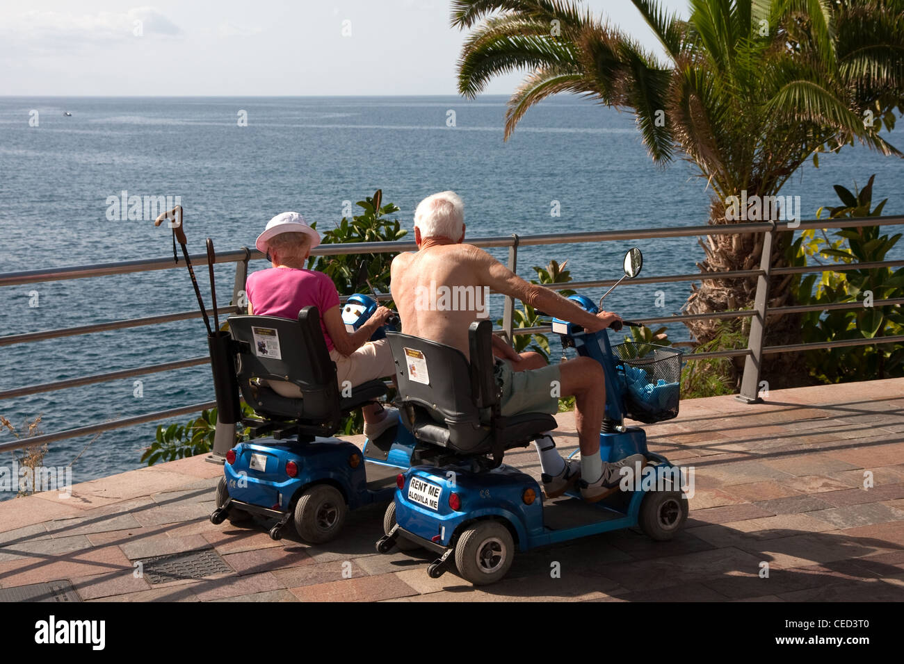 Elderly couple on mobility scooters looking out to sea Stock Photo