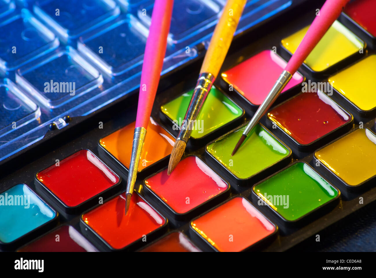 Closeup of a palette of watercolor paints with three brushes Stock Photo