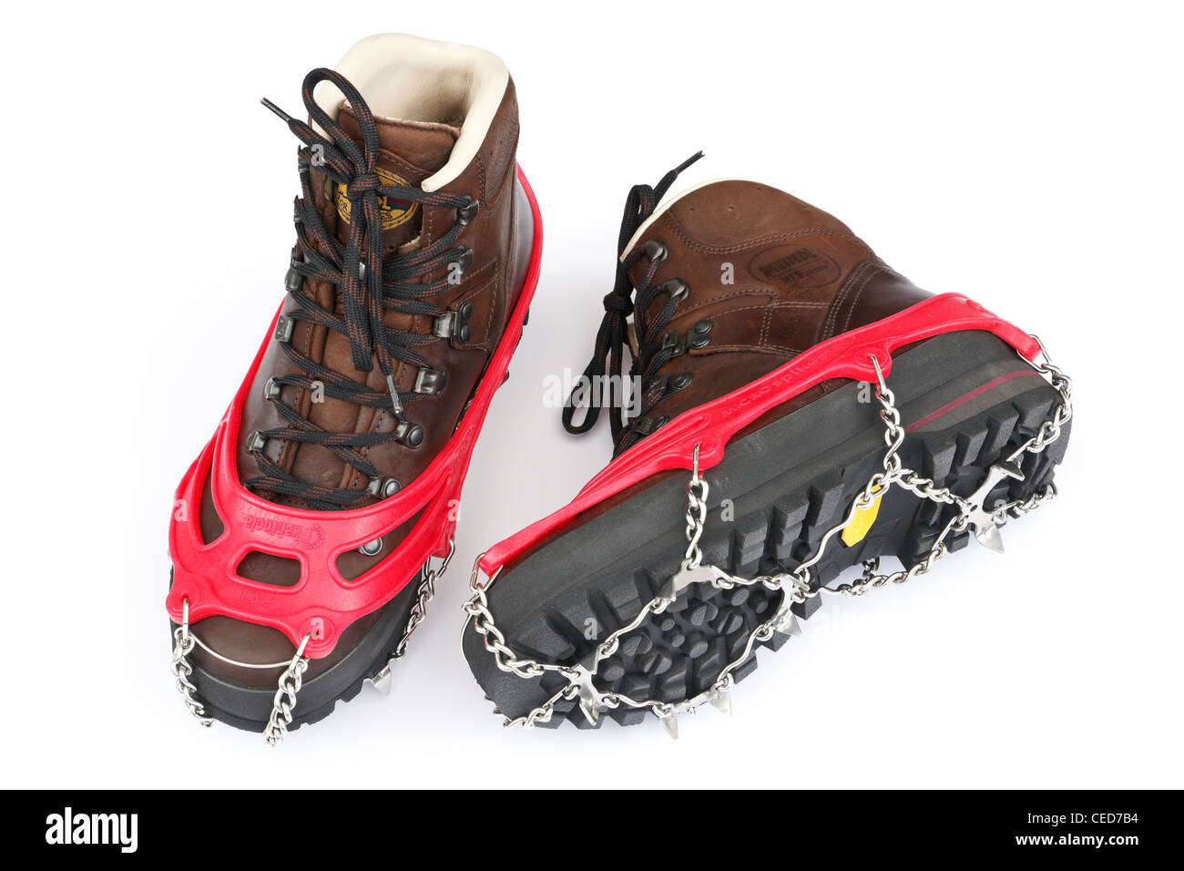 One pair of traditional brown leather walking boots with Kahtoola microspikes for using on ice and snow isolated on a white background. UK Stock Photo