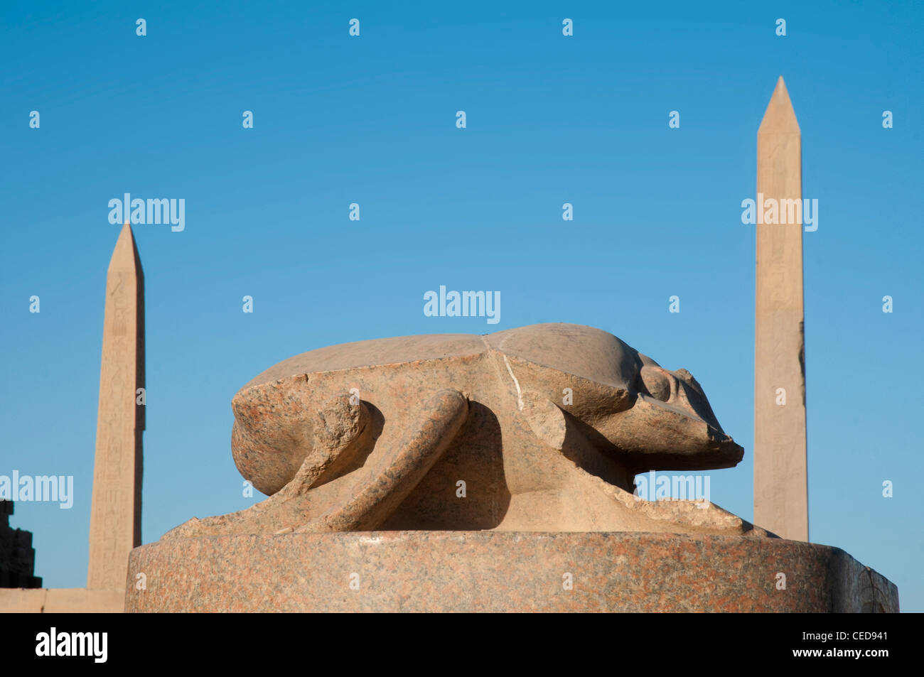 Statue of a giant scarab beetle representing Khepri, the sun, with obelisks beyond, at the Karnak Temple Complex, Luxor Stock Photo