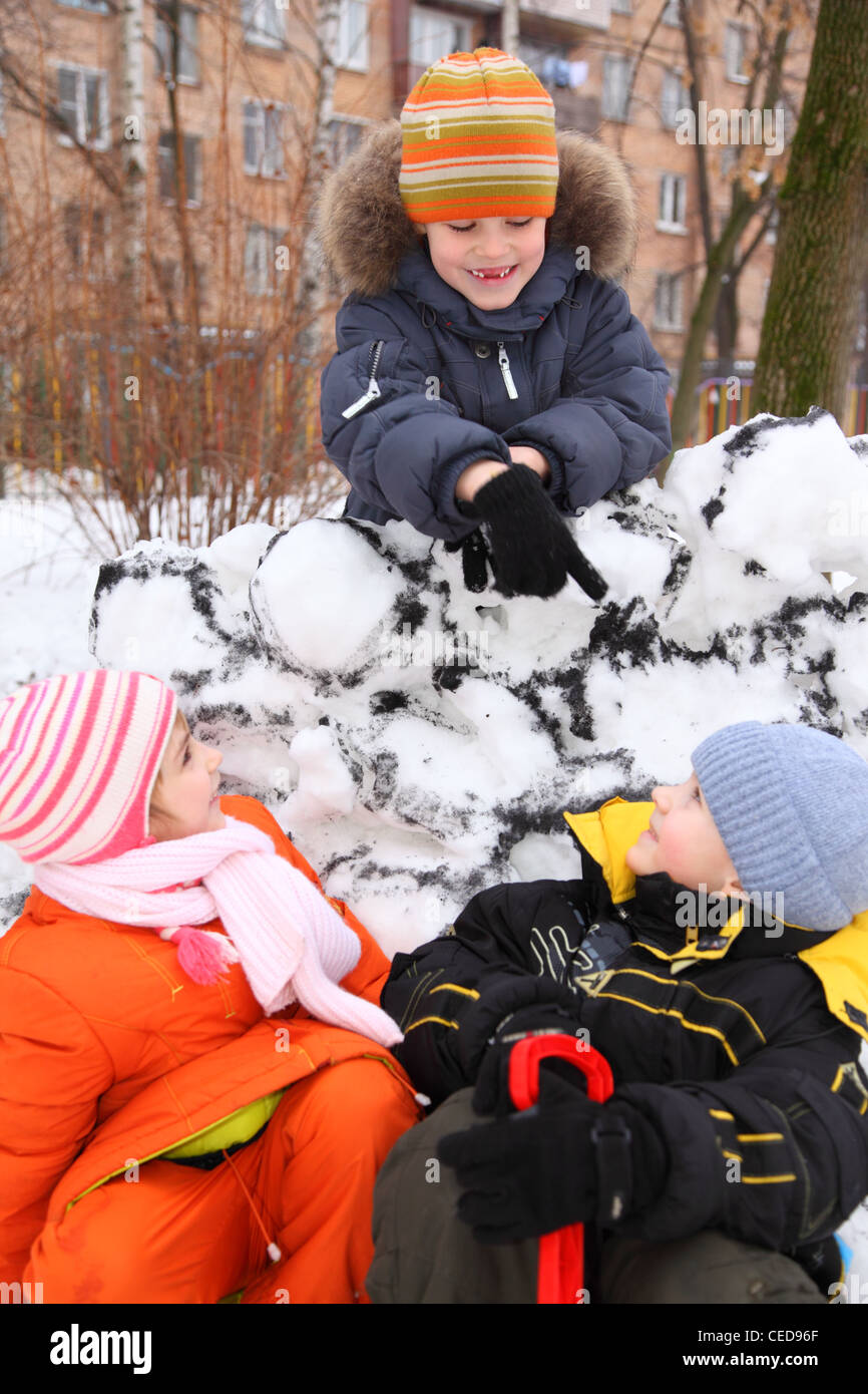 Three children at snow fortress in court yard Stock Photo