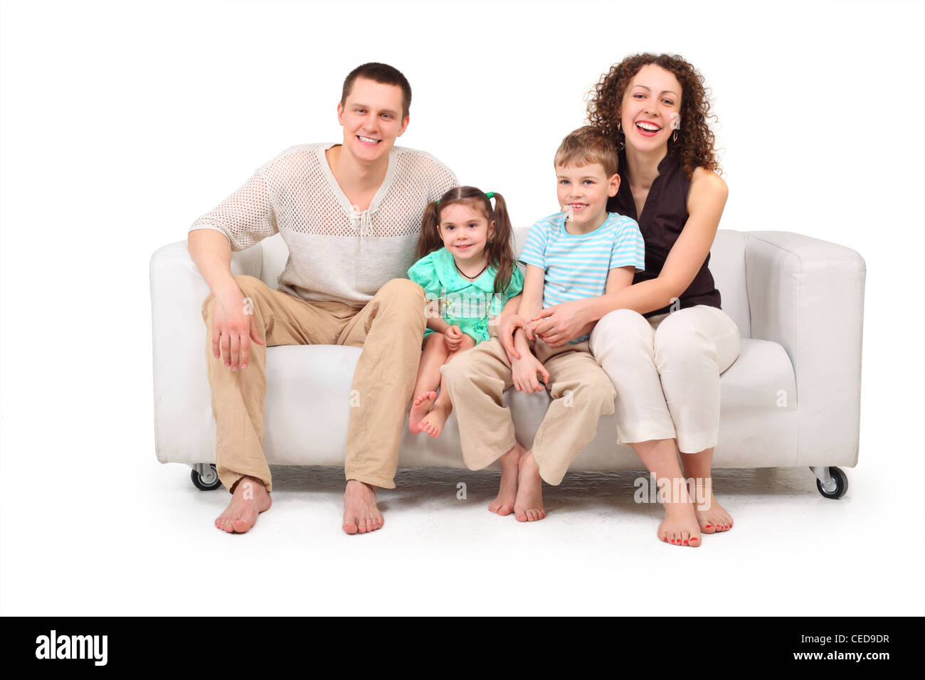 Family with two children sitting on white leather sofa Stock Photo