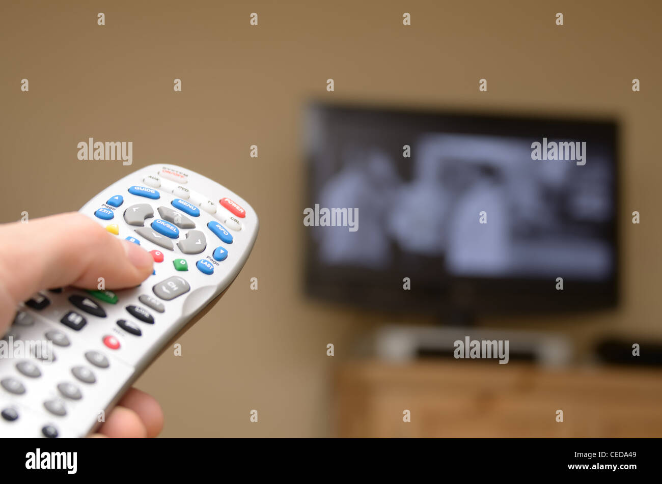 TTelevision remote in the foreground with selective focus and television in the background. Stock Photo