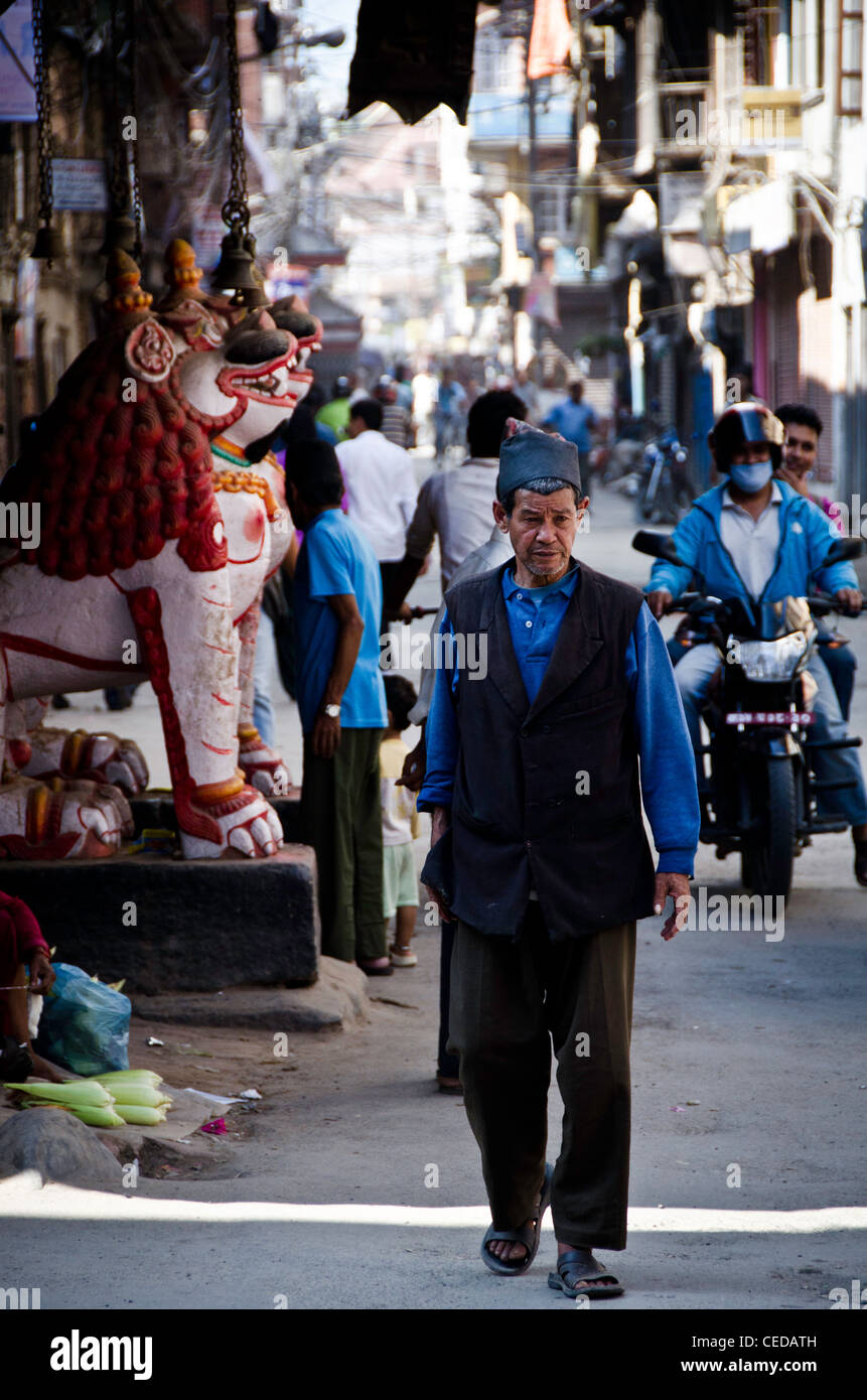 A man in traditional Nepalese dress walks down the street in old city Kathmandu, Nepal Stock Photo