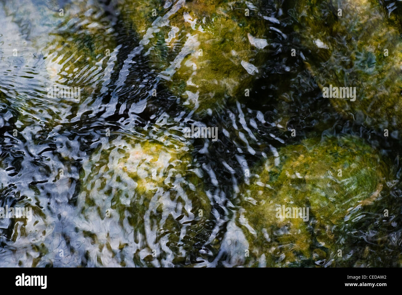 Boulders under and ripples in surface of water Stock Photo - Alamy