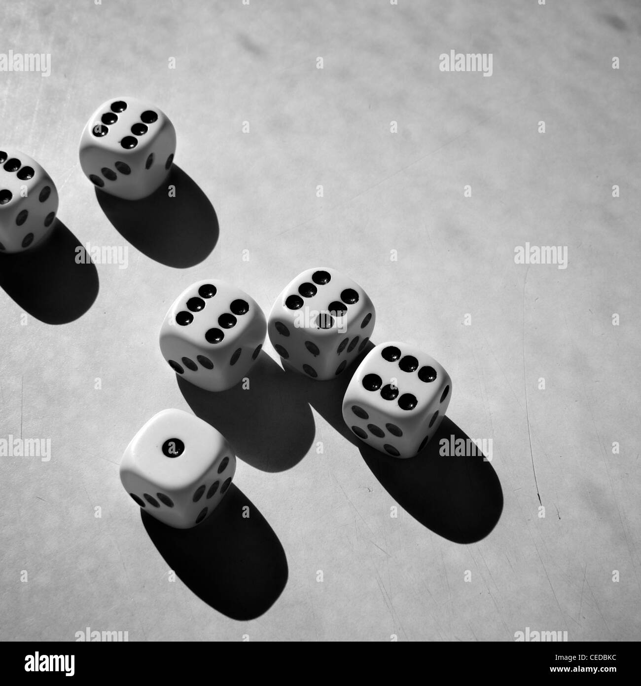 Six dices on a grungy scratched surface. Cropped image. Squared format. Black and white photo. Stock Photo