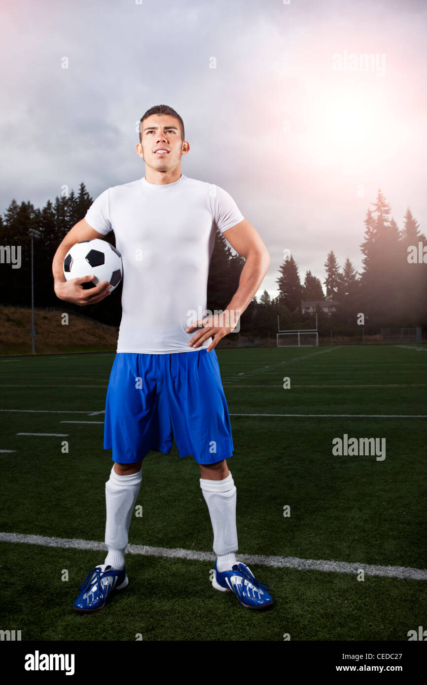 Hispanic athlete standing with soccer ball Stock Photo