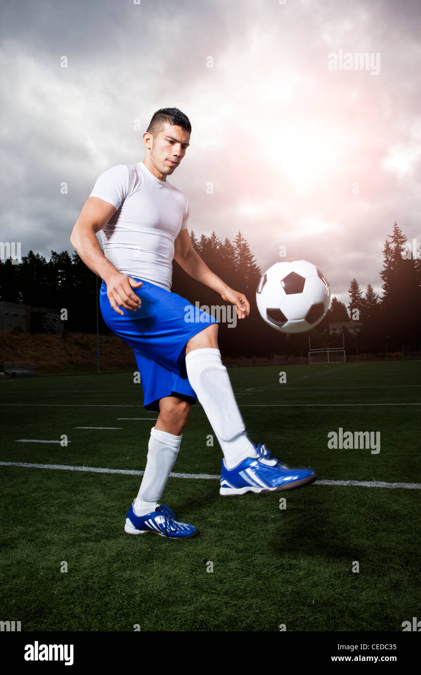 Hispanic athlete kicking soccer ball Stock Photo
